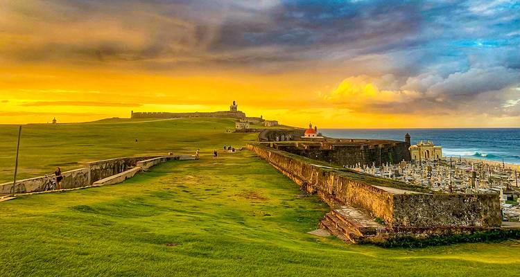 Vistas panorámicas de paisajes verdes exuberantes con una puesta de sol dramática.