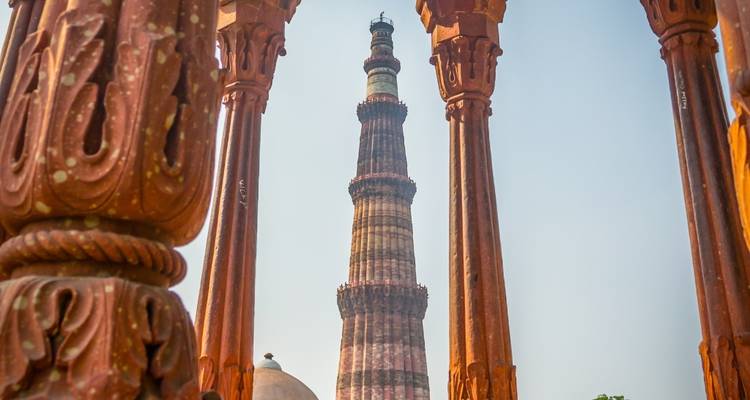 Qutub Minar framed by intricately carved pillars.