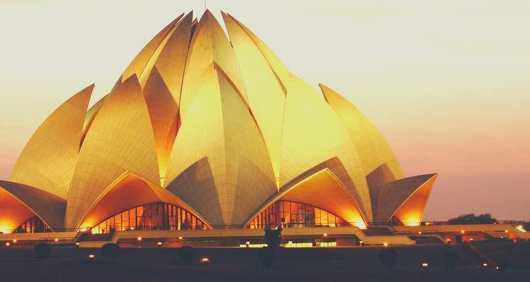 Lotus Temple illuminated in warm tones at dusk.