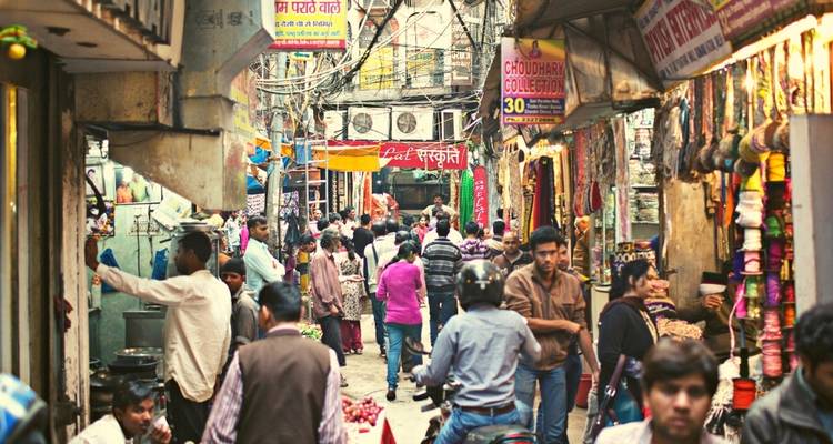 Busy street market in New Delhi with vendors and customers.