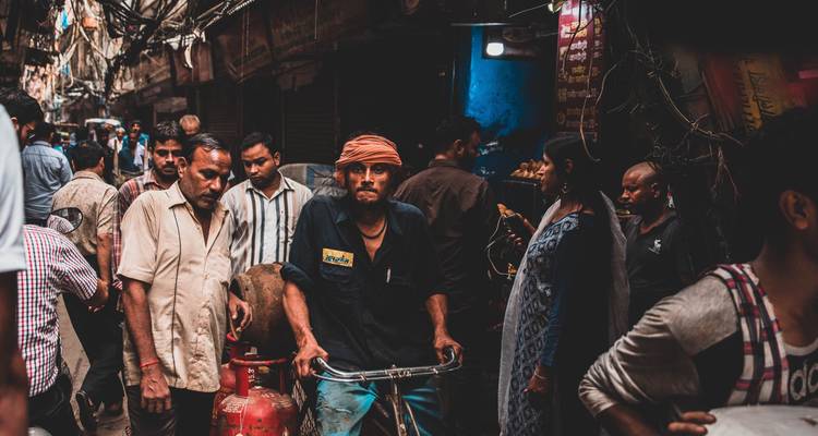 Crowded street scene with locals and a man on a bicycle.