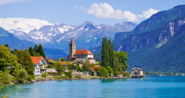 Swiss village by a lake with mountains in the background.