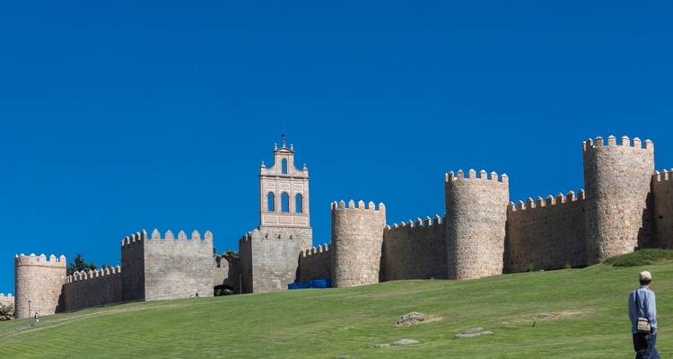 Ville fortifiée avec un mur fortifié sur une colline herbeuse.