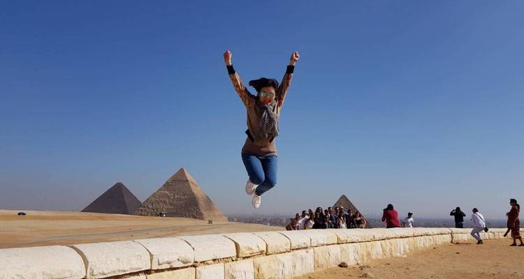 Persona saltando con pirámides en el fondo.