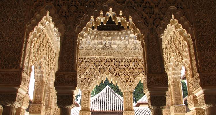 Ingewikkeld uitgesneden bogen met een uitzicht op daken daarachter.