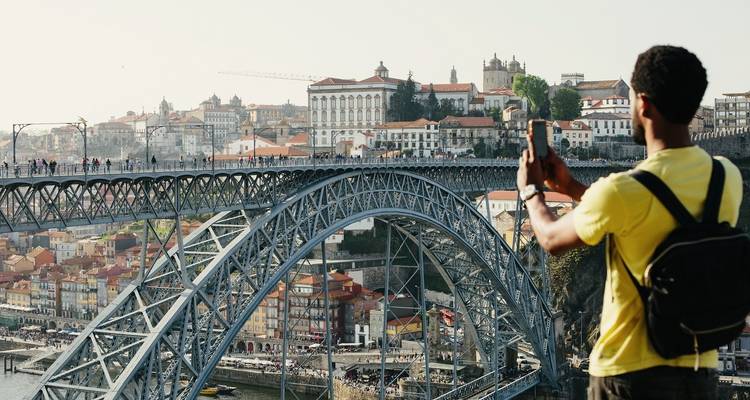 A person taking a photo of the Dom Luis I Bridge and cityscape.