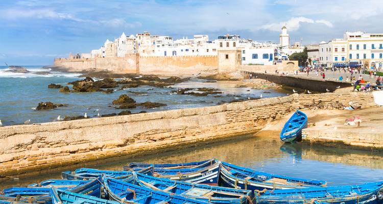 Kuststad met blauwe vissersboten en historische gebouwen.