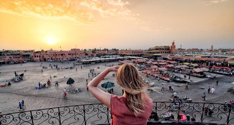Eine Frau, die bei Sonnenuntergang einen belebten Marktplatz überblickt.