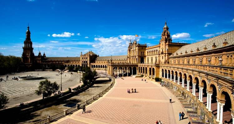 Groot historisch plein met ingewikkelde torens en veel toeristen.