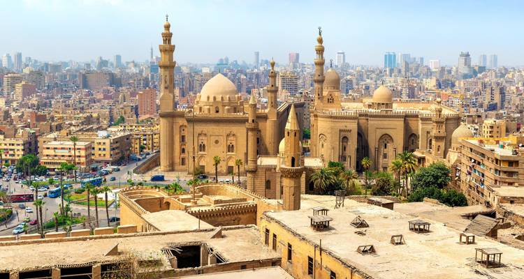 Historical mosque complex in city with modern skyline view.