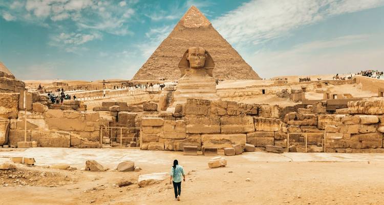 Famous pyramid and sphinx with people walking around.
