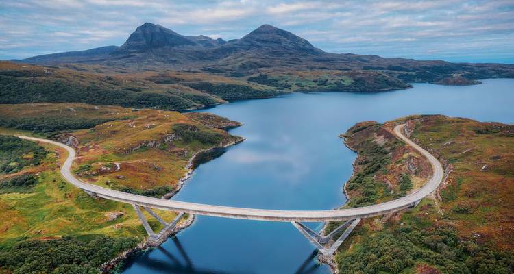 Pont pittoresque au-dessus d'un plan d'eau avec des montagnes.