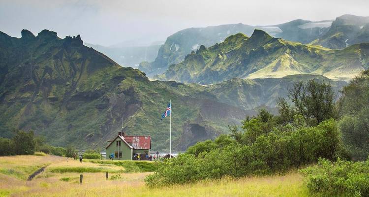 Paisaje montañoso en Islandia con una casa pequeña y bandera.