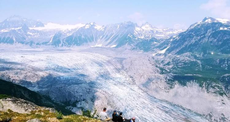 Groupe observant un vaste glacier au milieu d'un paysage montagneux.