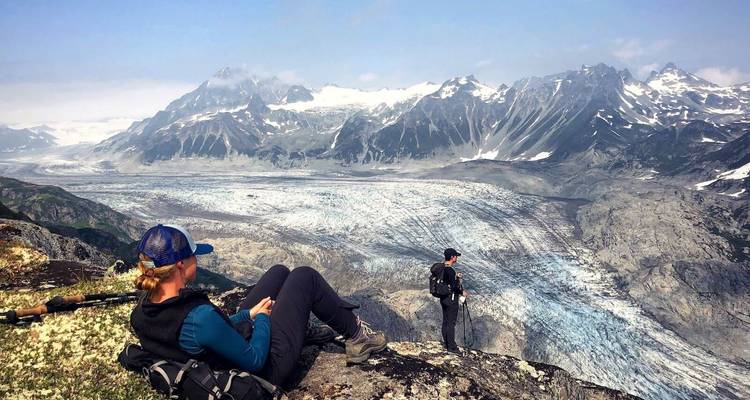Des randonneurs profitant de la vue d'un glacier étendu entouré de montagnes.