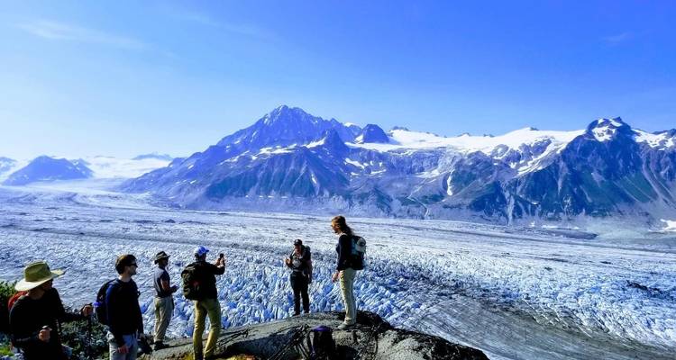 Des gens admirant un vaste paysage glaciaire avec des sommets imposants.