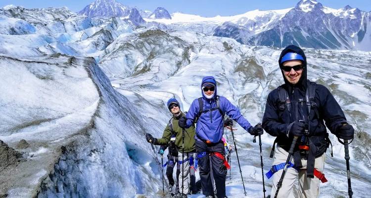 Randonneurs équipés pour l'exploration glaciaire posant devant un décor montagneux et glacé.