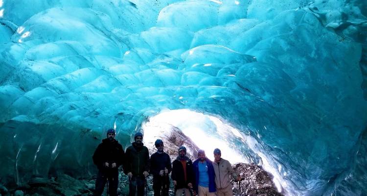 Groupe debout à l'intérieur d'une grotte de glace d'un bleu éclatant.