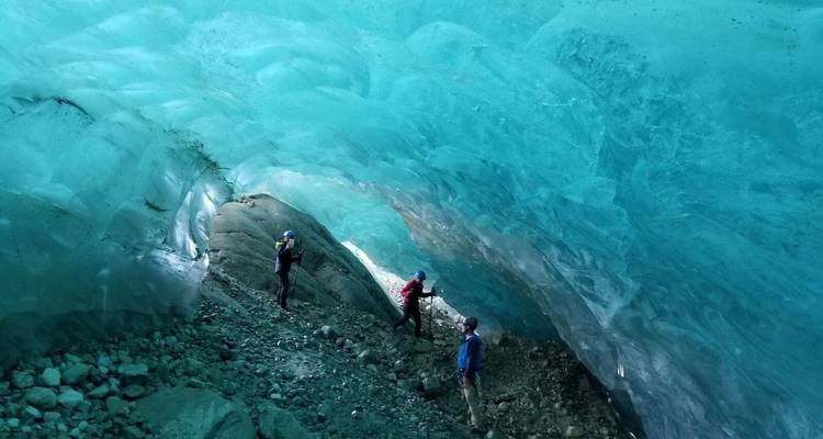 Des gens traversant une grande grotte de glace.