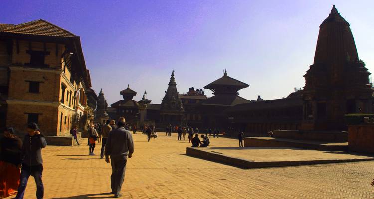 Einheimische und Touristen erkunden den Kathmandu Durbar Square, der mit alten Tempeln und Backsteinhöfen gesäumt ist.