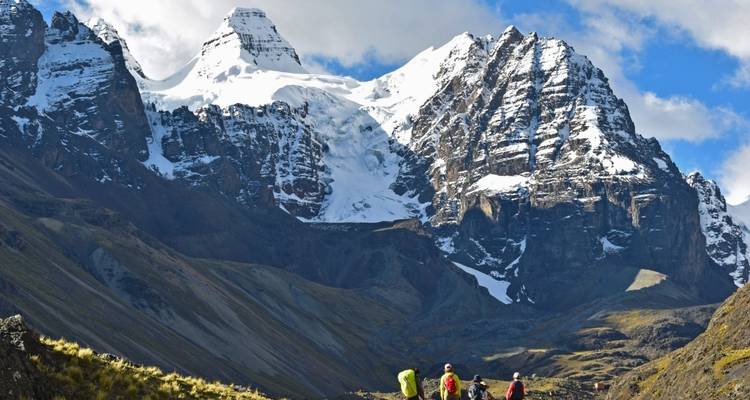 Hikers walking towards snow-covered mountains.