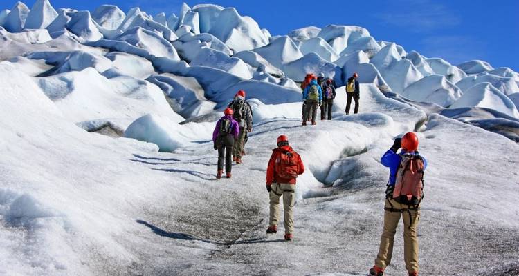 Group of hikers with gear on a glacier.