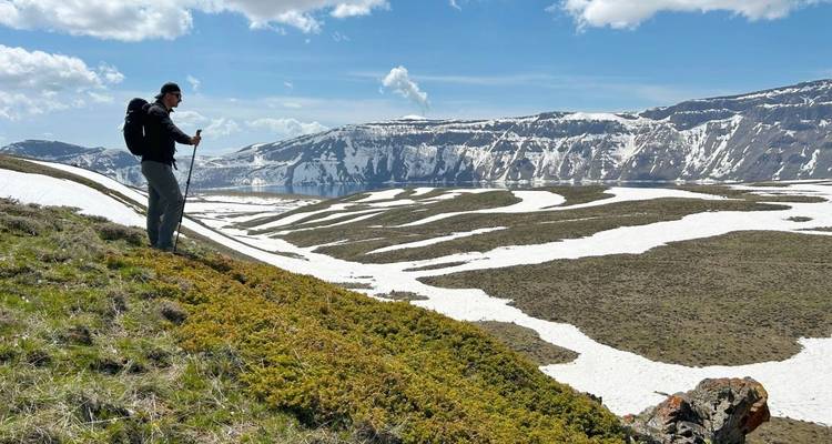 Persoon die wandelt in een bergachtig besneeuwd landschap met heldere lucht.