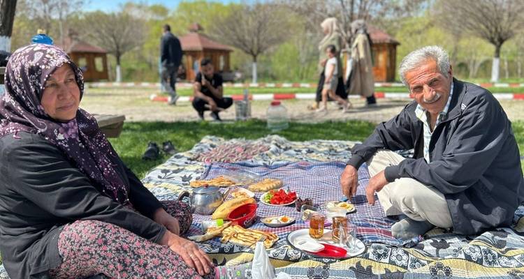 Een koppel op een picknick dat geniet van eten op een deken in een park.