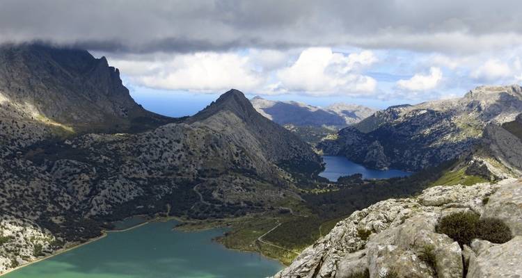 Vue panoramique sur des crêtes montagneuses avec une vallée et des lacs.