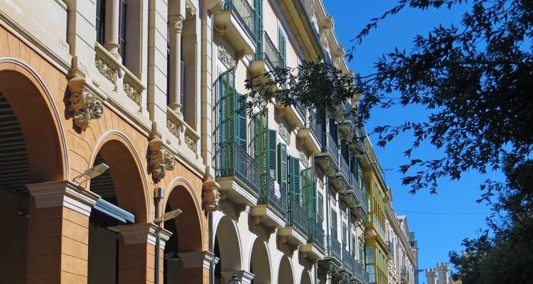 Une rangée de bâtiments colorés avec des balcons sous un ciel dégagé.