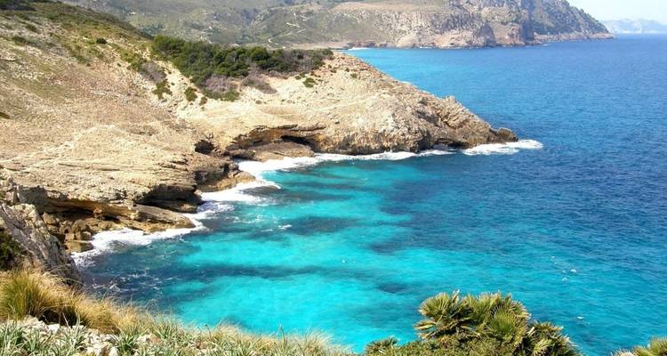 Côte rocheuse avec une eau bleue claire et des vagues qui se brisent.