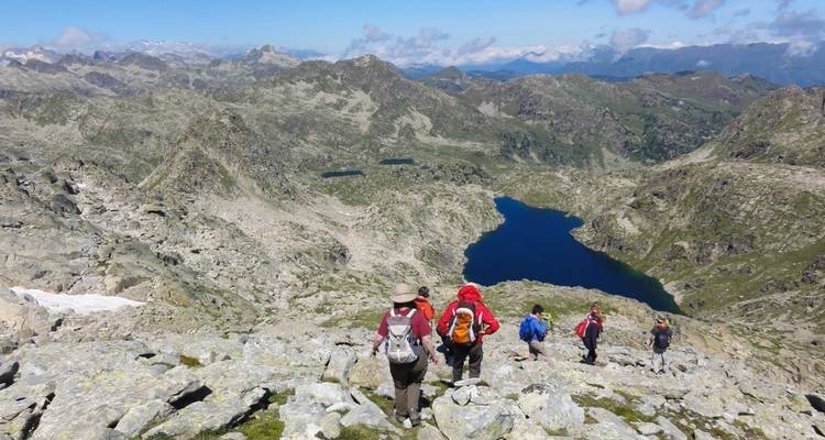 Wandelaars op een bergpad met uitzicht op alpine meren.
