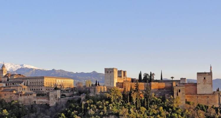 Vista del palacio de la Alhambra con montañas al fondo durante el día.