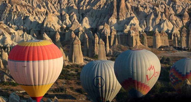 Hot air balloons floating over a rugged landscape at dusk.