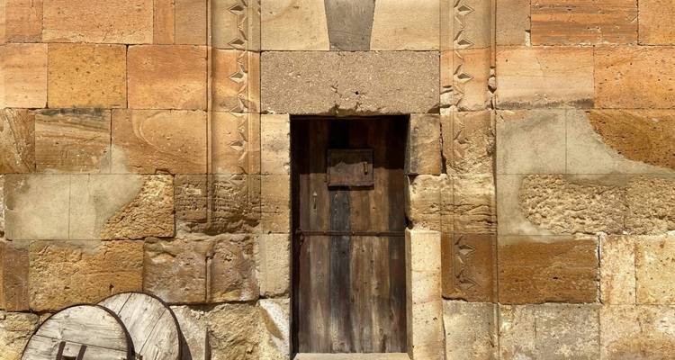 Old rustic door with stone wall surrounding it.