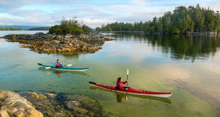 Kayakistas remando en aguas tranquilas cerca de pequeñas islas.
