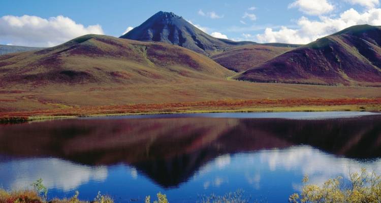 Mountain landscape with rolling hills reflected in a calm lake.