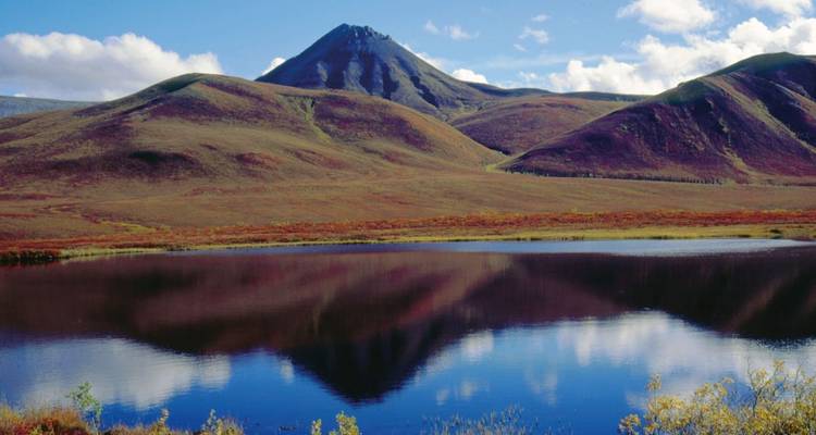 Mountain with autumn colors reflecting in a lake.