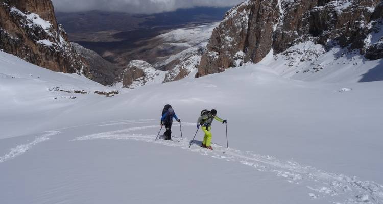 Dos esquiadores caminando por un valle nevado.