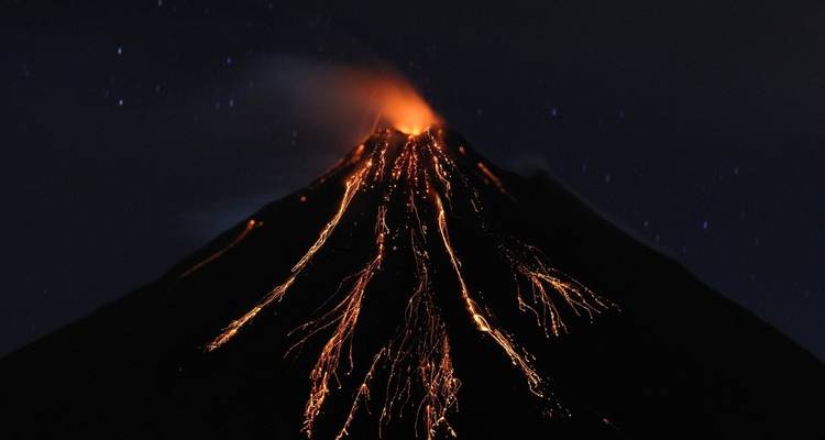 Lava flowing from an erupting volcano at night.