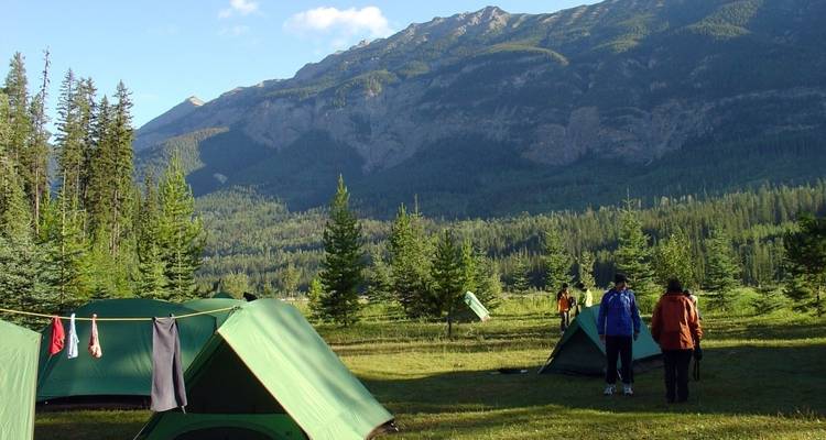 Zeltplatz mit Zelten in einer bewaldeten Berglandschaft.