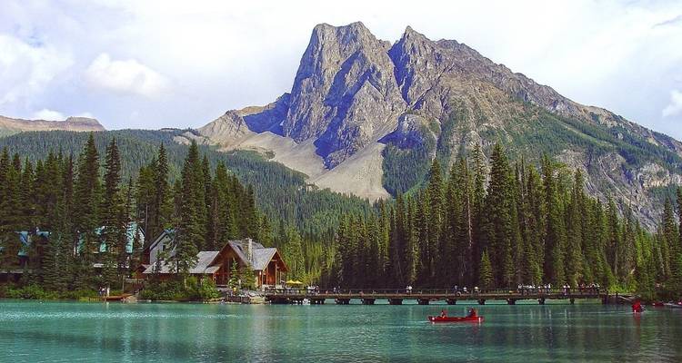 Ein Seeblick mit einer Holzhütte und Bergen im Hintergrund.