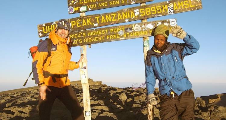 Zwei Personen posieren am Uhuru Peak Schild.
