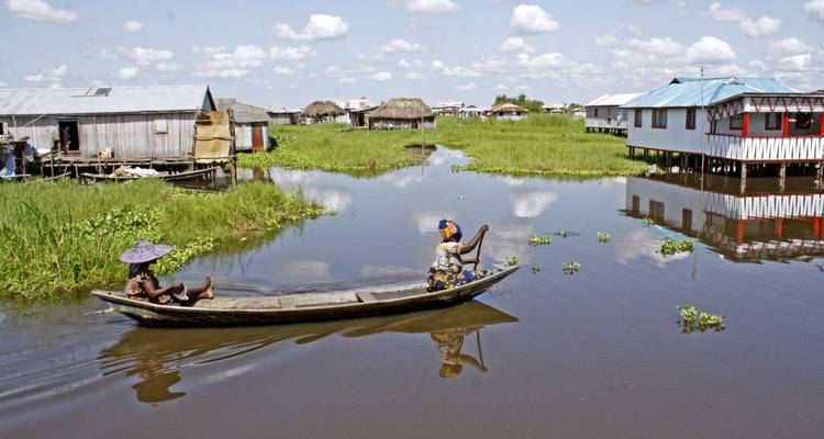 Deux personnes dans un canoë en bois sur une voie navigable.