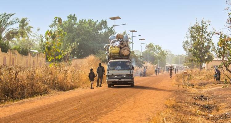 Véhicule chargé sur un chemin de terre dans une zone rurale.