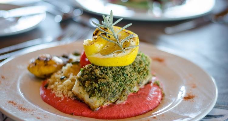 Elegantly plated dish with herbs and a lemon slice.