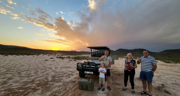 Family enjoying a sunset safari with a vehicle in the wilderness.