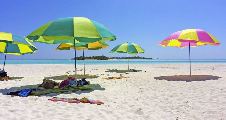 Colorful beach umbrellas on a sandy beach with turquoise water.