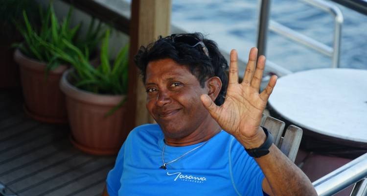 Person sitting on a boat with the sea in the background, waving.