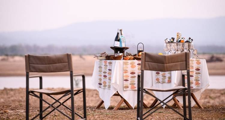 Ein Outdoor-Dining-Bereich mit Tischen und Stühlen in der Nähe eines Flusses.

Alternative translation:
Eine Außengastronomie mit Tischen und Stühlen nahe einem Fluss.